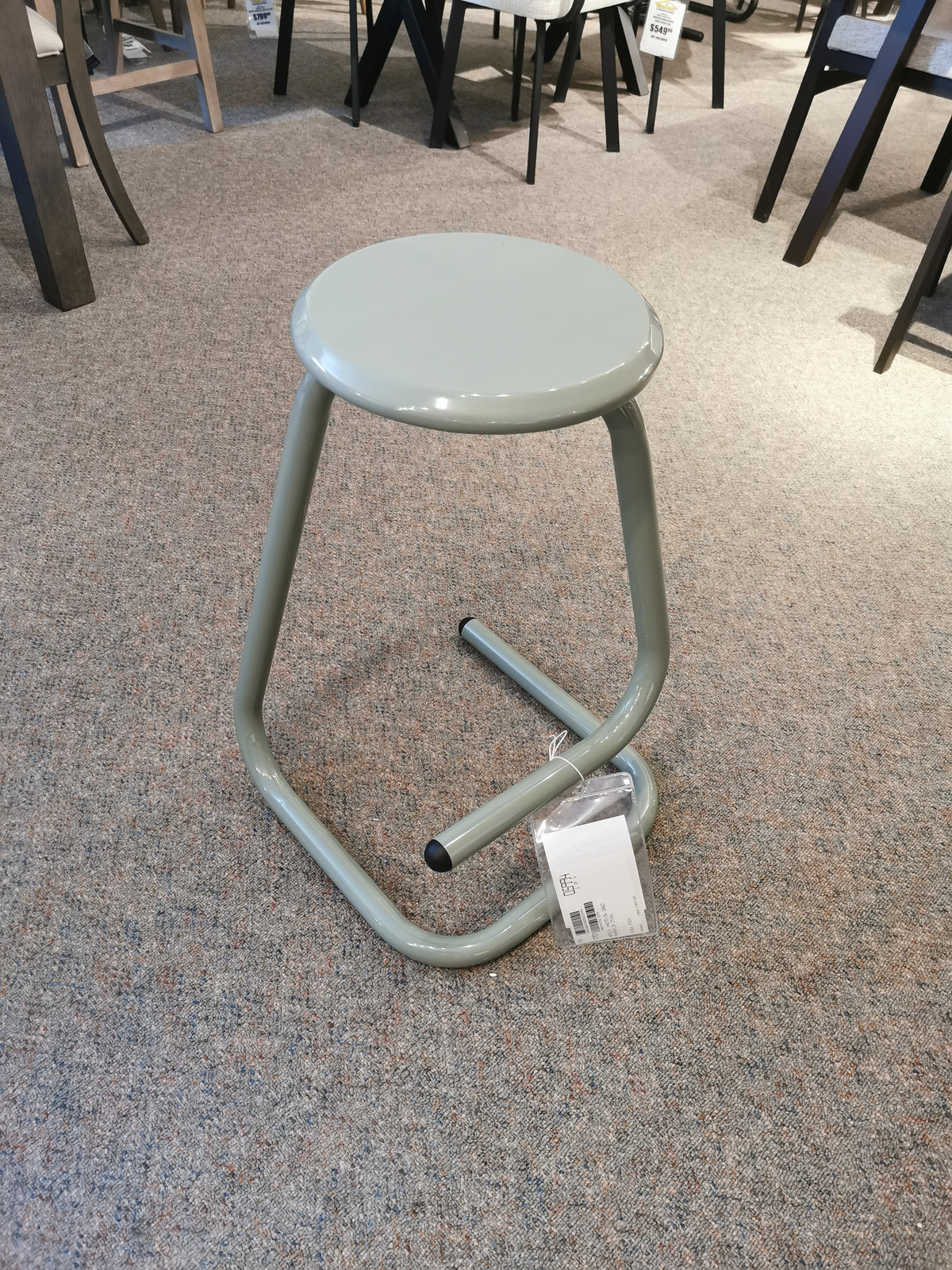 A 44070-26 Paperclip Stool by Amisco, with a light green seat and geometric frame, exudes modern elegance on carpet.