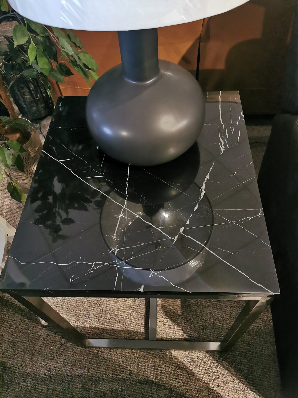 The T5760 Kira End Table by Magnussen offers modern sophistication with black marble and white veins, complemented with a lamp.