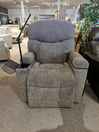 A Golden Maya UC-566 Med Power Lift Chair in gray with a side tray and reading light is displayed in a showroom.