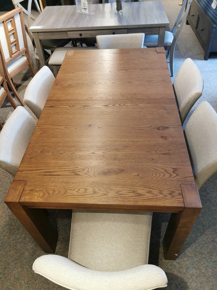 Bloc Dining Package by Donald Choi: solid rubberwood table with six beige upholstered chairs displayed in store.