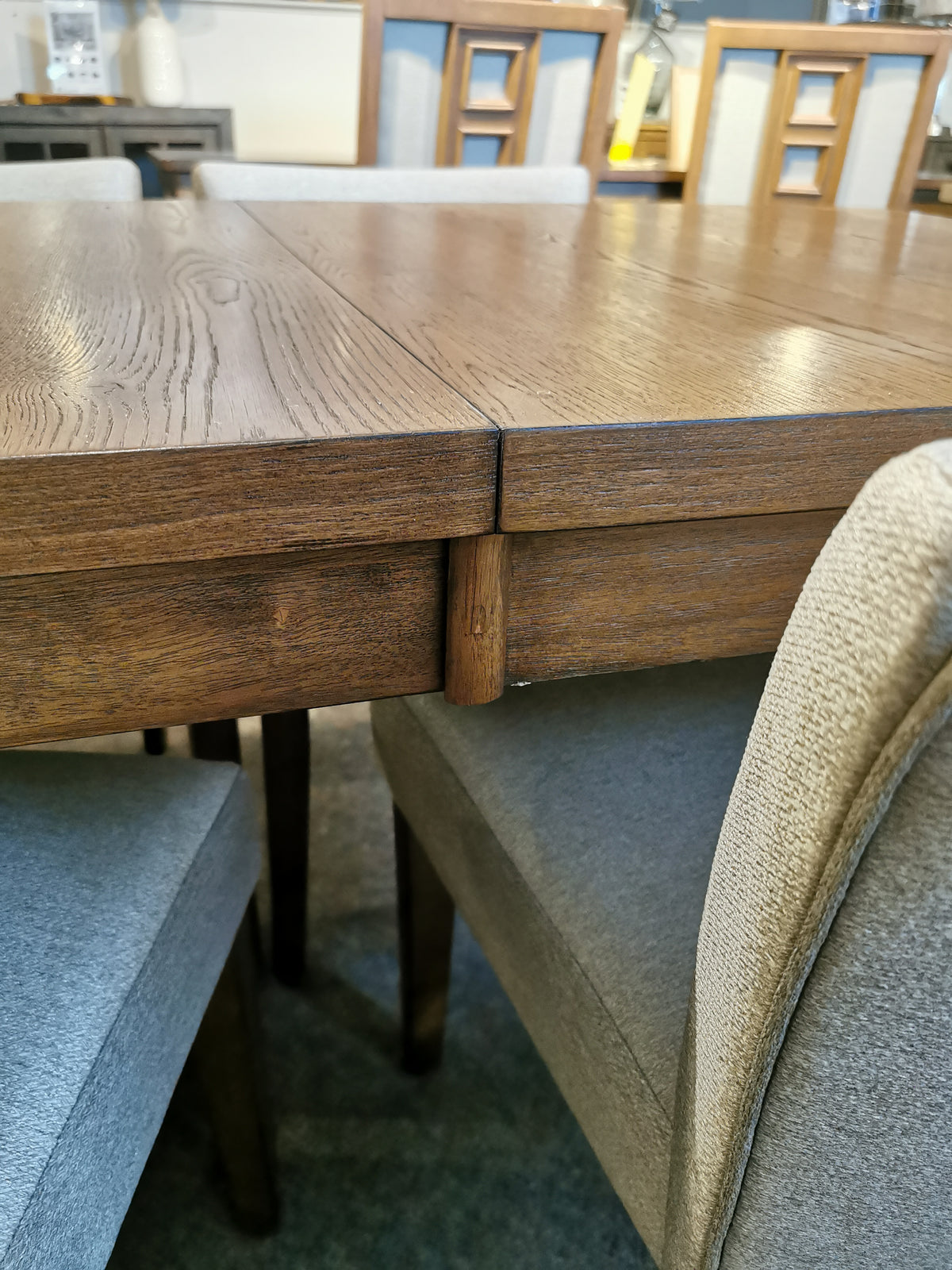 Close-up of the Bloc Dining Package by Donald Choi, featuring walnut oak veneer and beige chairs on a carpeted floor.