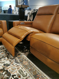 A Timberland Power Loveseat by Aurora Furniture sits on a patterned rug, featuring a power headrest and extended footrest.