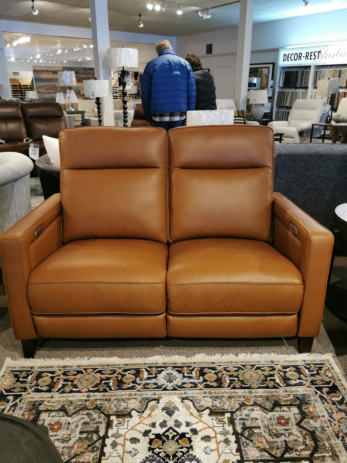 Timberland Power Loveseat by Aurora Furniture on a patterned rug with lamps and decor in the background.