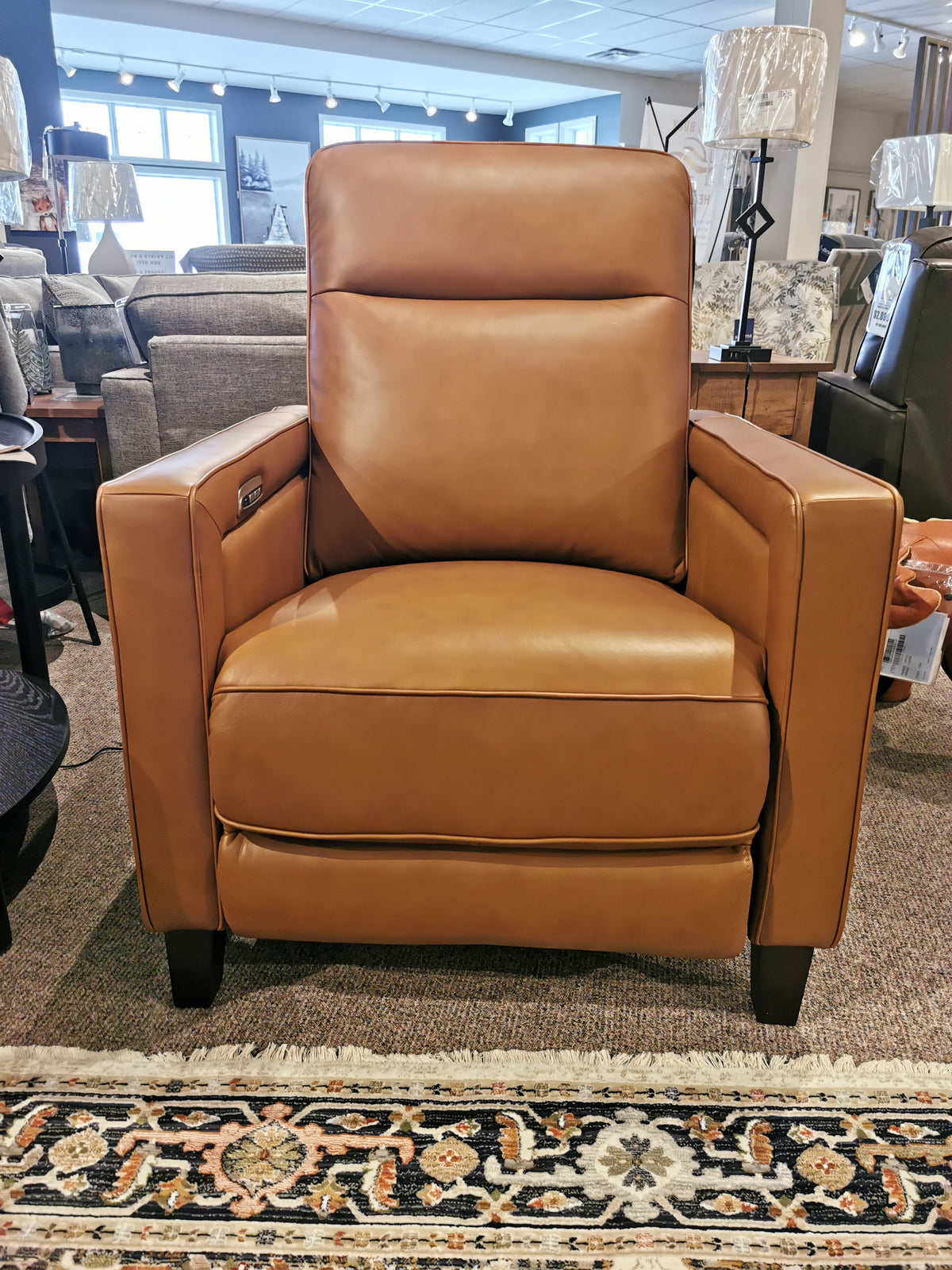 Timberland Power Chair, a brown leather recliner by Aurora Furniture, with power headrest on a rug in store display.