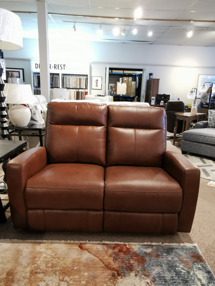 Aurora Furniture's Muskoka Power Loveseat, brown leather with moccasin stitching, displayed among sofas and decor.