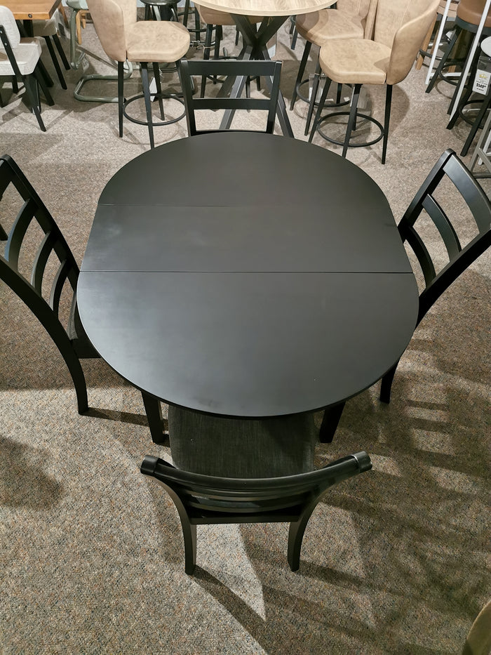 The Emma Dining Package by Donald Choi, featuring a black oval table and 5 chairs, is showcased in a furniture showroom.