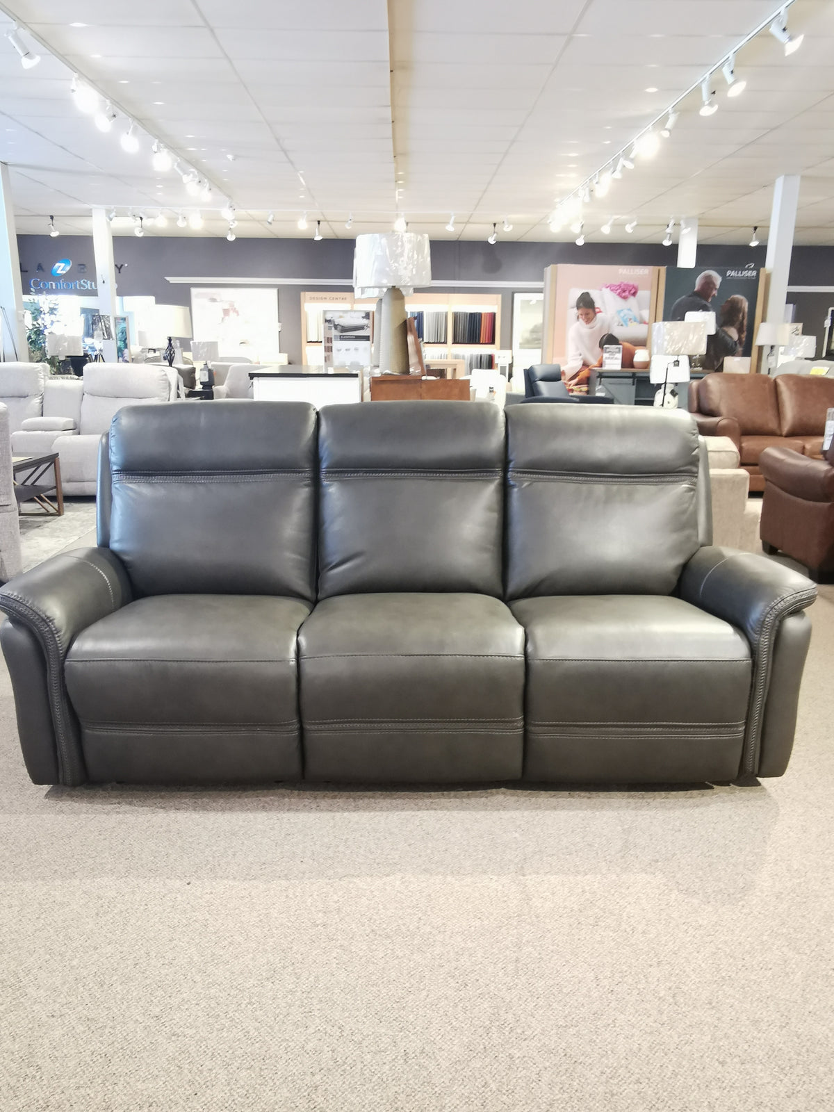 A Cascade Power Sofa from Aurora Furniture on display in a furniture store showroom.