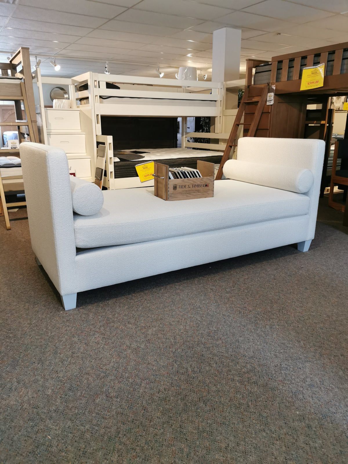 A Vaughan Bassett 835 Twin DayBed with cylindrical pillows is showcased with a wooden crate on top.