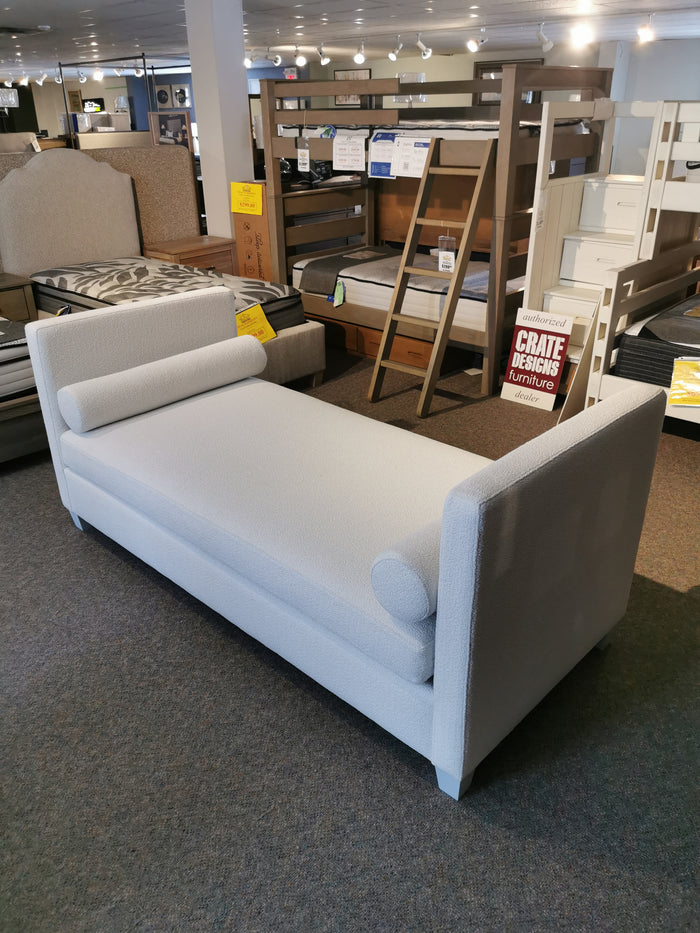 Vaughan Bassett's 835 Twin DayBed, with gray upholstery and oak accents, features bolster cushions in a furniture store.