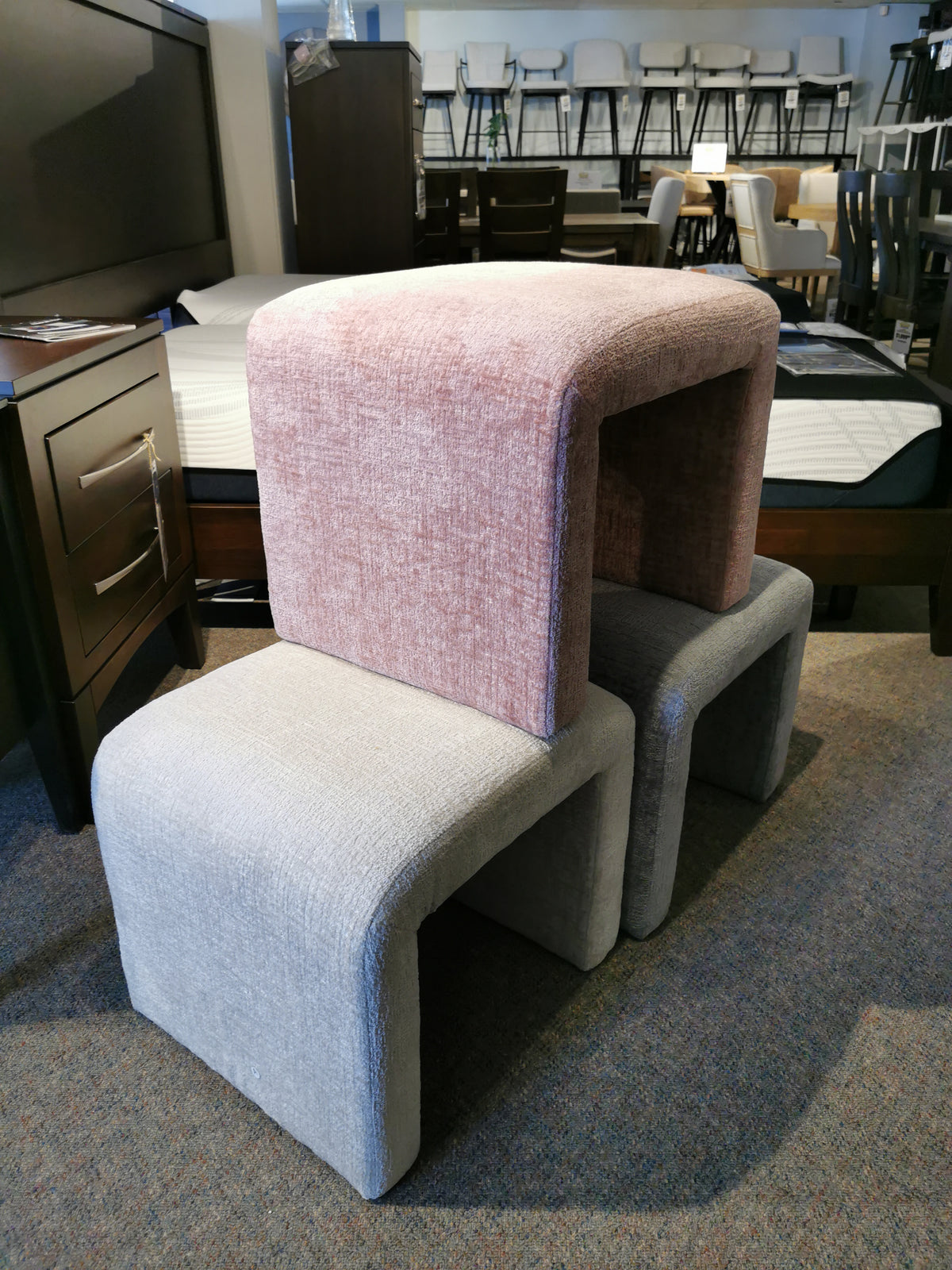 Three luxe chenille fabric stools are stacked with a bed and Jofran's Sophia Petite Bench visible in the background.