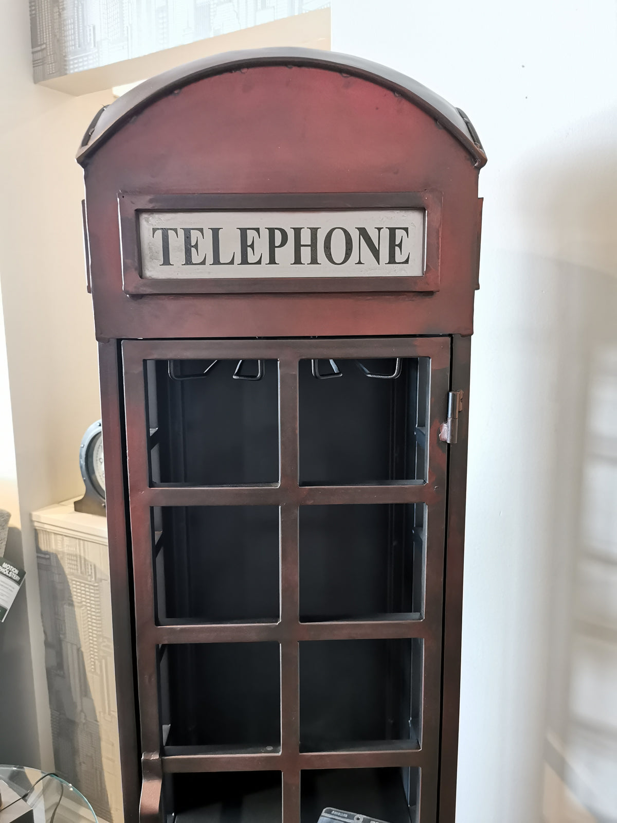 The Jofran Telly Vintage Telephone Booth Bar has a "TELEPHONE" sign, glass-paneled door, and iron accents.