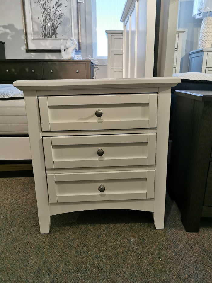 In a furniture store, the Vaughan Bassett BB29 Bonanza Nightstand with three drawers and round knobs sits on the carpet.