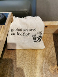 Natural materials shaped by expert artisans form a "Global Archive Collection" cloth bag on the Fairchild Checkerboard C-Table.