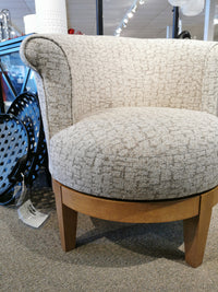 The Attica Swivel Chair by Best is a beige upholstered chair with a wooden base, ideal for cottage-styled rooms.