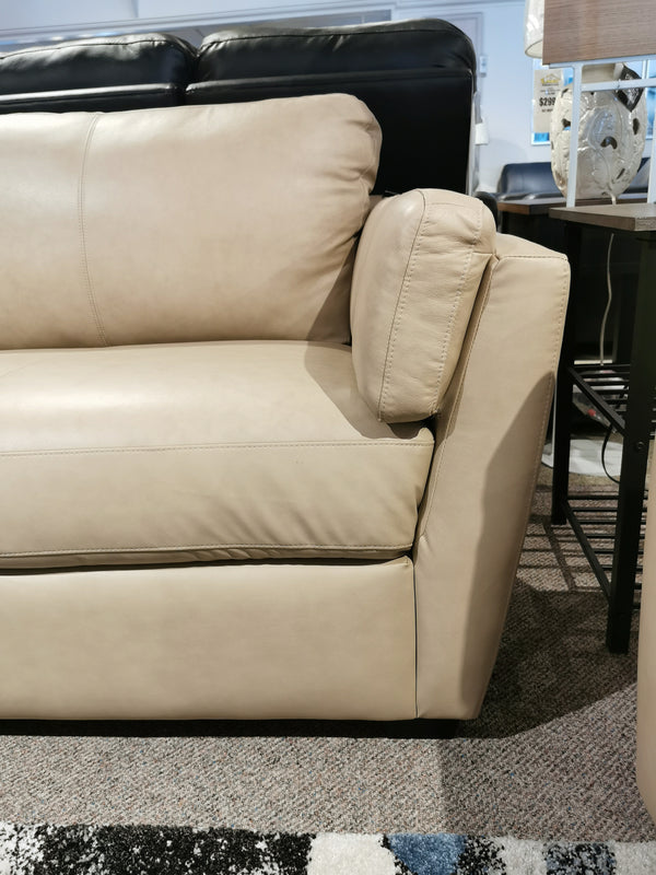 Close-up of the Palliser 77882 Payton Sofa in beige leather, featuring minimalist decor on a patterned transitional carpet.