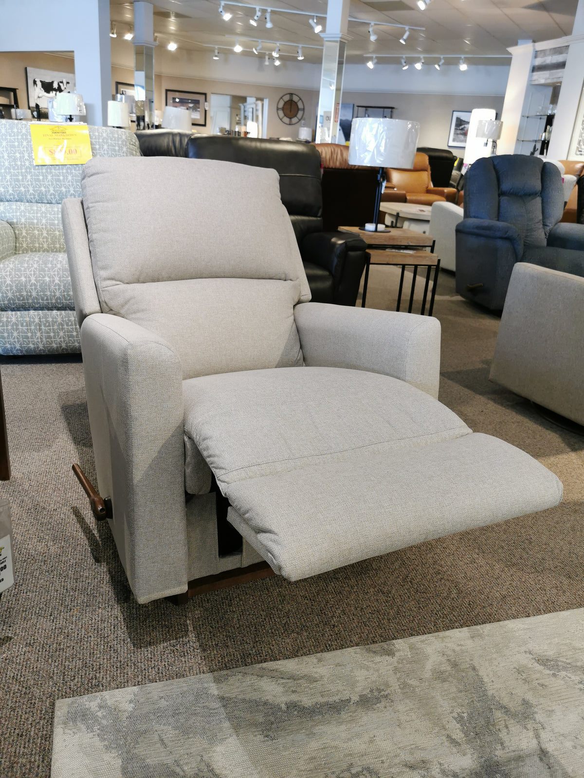 In the showroom, the La-z-boy 700 Wynne Rocker Recliner in beige offers comfort among various living room seating options.