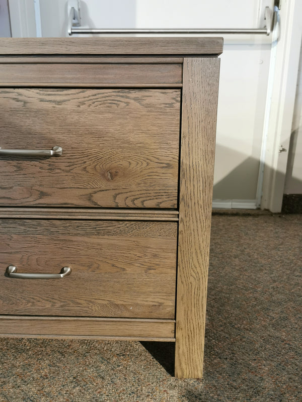 Close-up of a Vaughan Bassett 831 Tide & Timber Nightstand corner, with metal handles, on a carpeted floor.