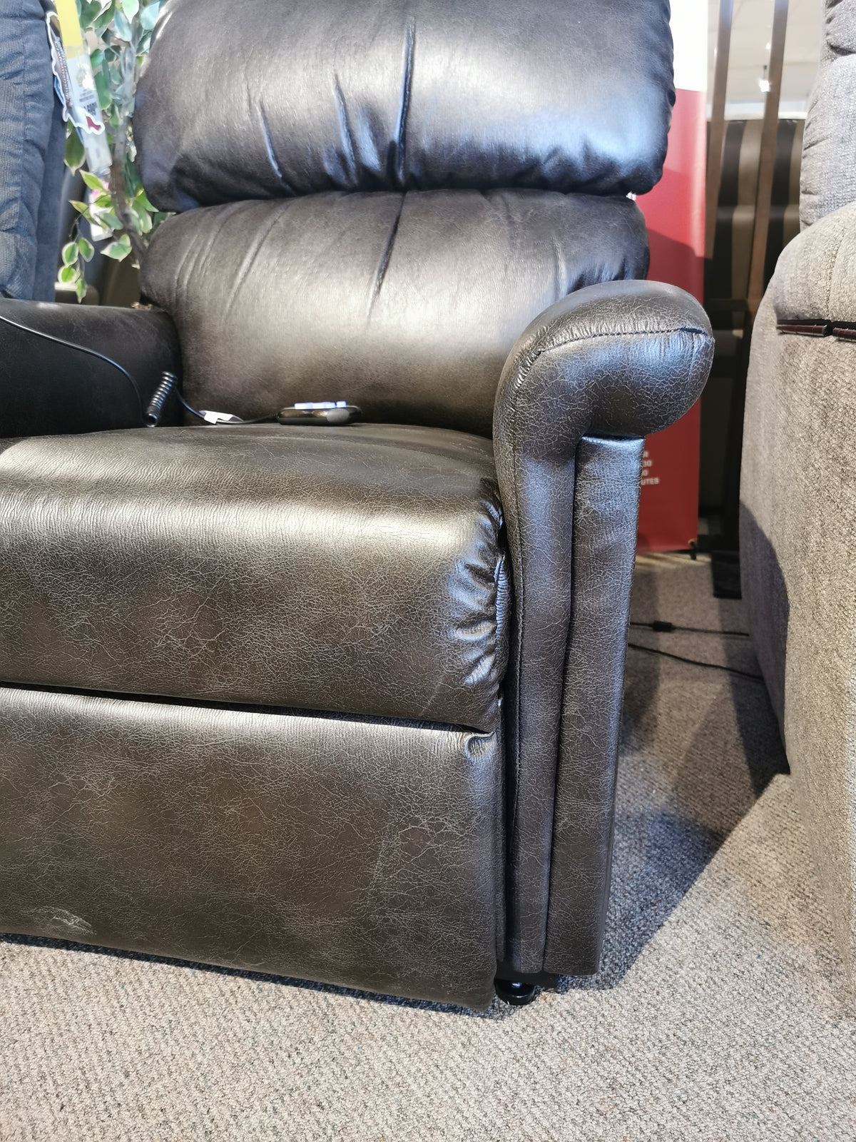 A plush black leather Austin UC-342 Power Lift Chair by Golden on carpet, with a seamed back and padded armrest.