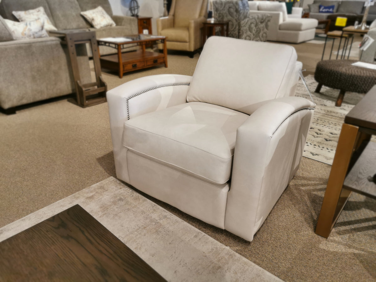 The 741 Leather Swivel Chair by Leather Craft sits on a rug, with custom upholstered chairs and tables nearby in the store.