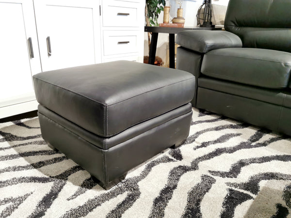 The Colorado Leather Ottoman by Leather Craft sits on a zebra-striped rug, enhancing the sofa in a room with white cabinets.