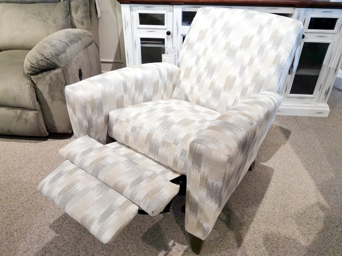 The 431 Scarlett High-Leg Recliner by La-Z-Boy, a beautifully handcrafted piece made in the U.S.A., is elegantly displayed in a showroom. This gray patterned push-back recliner features an extended footrest, perfectly complementing its surroundings of carpet and cabinets.