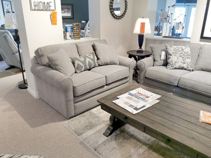 A showroom features two 494 Collins Stationary Loveseats, a wood coffee table with magazines, and a La-z-boy lamp.