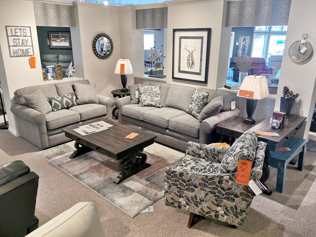 Showroom with a La-z-boy 494 Collins sofa, floral armchair, coffee table, lamps, wall art, and mirrors.