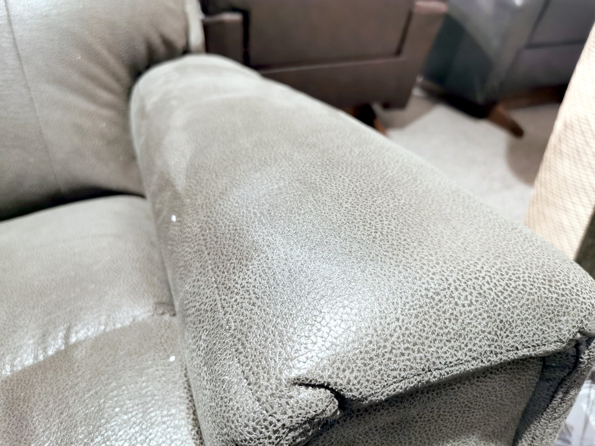 Close-up of a gray leather armrest from the La-Z-Boy 757 Apollo Reclining Sofa, showcasing its visible texture and stitching details, with bucket chaise seats and surrounding furniture subtly in view.