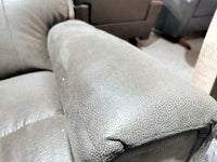 Detailed view of a green leather armrest on the 757 Apollo Reclining Loveseat by La-Z-Boy, highlighting its texture and stitching. The ensemble also features bucket chaise seats and split backs, with additional furniture pieces visible in the background.