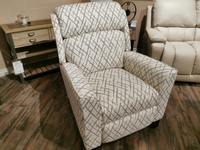 The 458 Rheeves Hi-Leg Recliner by La-z-boy, featuring a cozy patterned upholstery and sleek modern design with decorative wooden legs, rests on a wooden floor with a small wooden side table visible in the background.