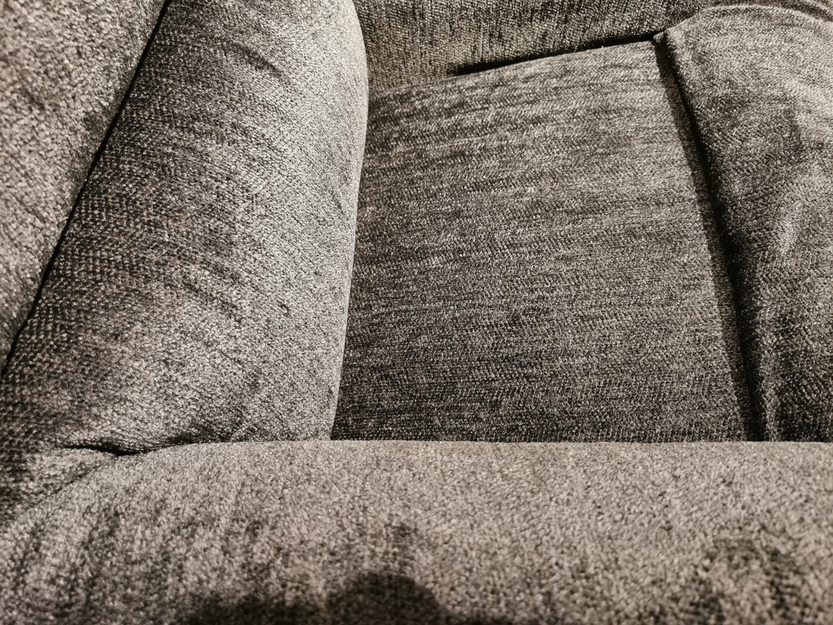 Close-up of a textured gray fabric sofa, highlighting the armrest and seat cushion with visible stitching and fabric pattern, reminiscent of the comfort found in a 519 Astor Rocker Recliner by La-Z-Boy.