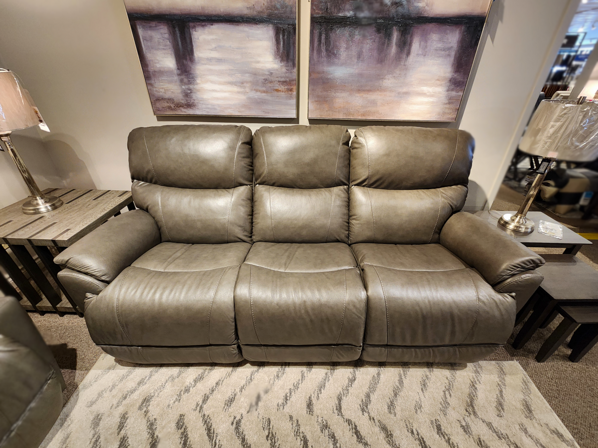 A La-Z-Boy 724 Trouper reclining sofa with sculpted bucket seats is in a showroom, flanked by matching tables and lamps.