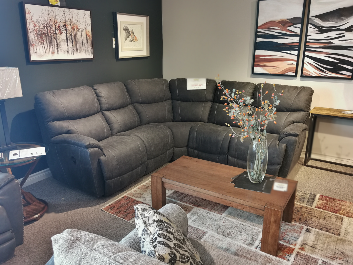 The living room setup features a dark La-Z-Boy 724 Trouper Reclining Corner Sectional with customizable fabrics, complemented by a wooden coffee table and nature-themed wall art.