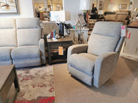 La-z-boy's 747 Finley Rocker Recliner in gray, with modern lines, sits near a rug and side table in the showroom.