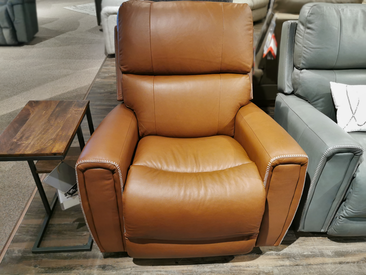 Experience modern comfort with the 757 Apollo Rocker Recliner by La-Z-Boy, featuring a plush bucket seat and cushioned arms. This brown leather recliner sits elegantly beside a wooden side table on the showroom floor, inviting you to relax in style.