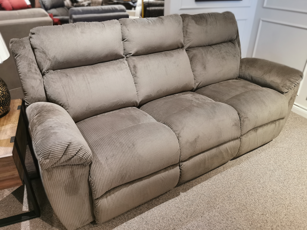 The 761 Joel Reclining Sofa by La-z-boy in gray features textured fabric, cushioned arm pads, and complements an indoor carpeted floor.