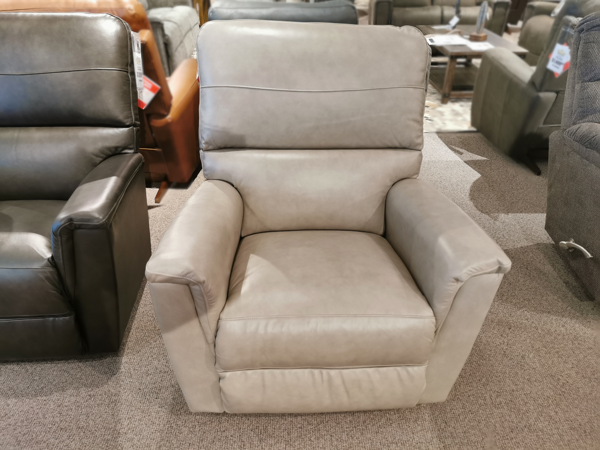 The La-Z-Boy 769 Ava Rocker Recliner in gray leather, a versatile option on the carpeted showroom floor, is surrounded by other recliners.