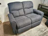 The 780 Hawthorn Power Reclining Loveseat by La-z-boy sits on a carpeted floor with a small side table in view.