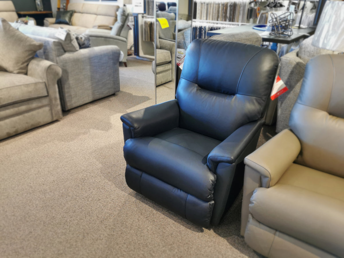 The La-Z-Boy 783 Aries Rocker Recliner, exemplifying both comfort and durability, is featured prominently in the furniture store showroom among a variety of sofas and other recliners.