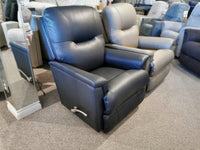 A black leather 783 Aries Rocker Recliner by La-Z-Boy is showcased in a furniture store, offering unparalleled comfort and durability. It sits alongside other recliners, resting on a carpeted floor for ultimate sophistication.