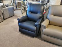 A La-Z-Boy 783 Aries Rocker Recliner in black sits on the carpeted floor of a furniture store, promising comfort and durability. It's elegantly positioned next to a beige reclining rocker, creating an inviting space for relaxation seekers.