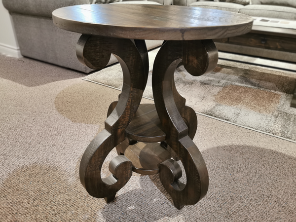 Magnussen's 2491 Bellamy Round Accent Table with a carved base, adds rustic charm to a cozy carpeted living room.