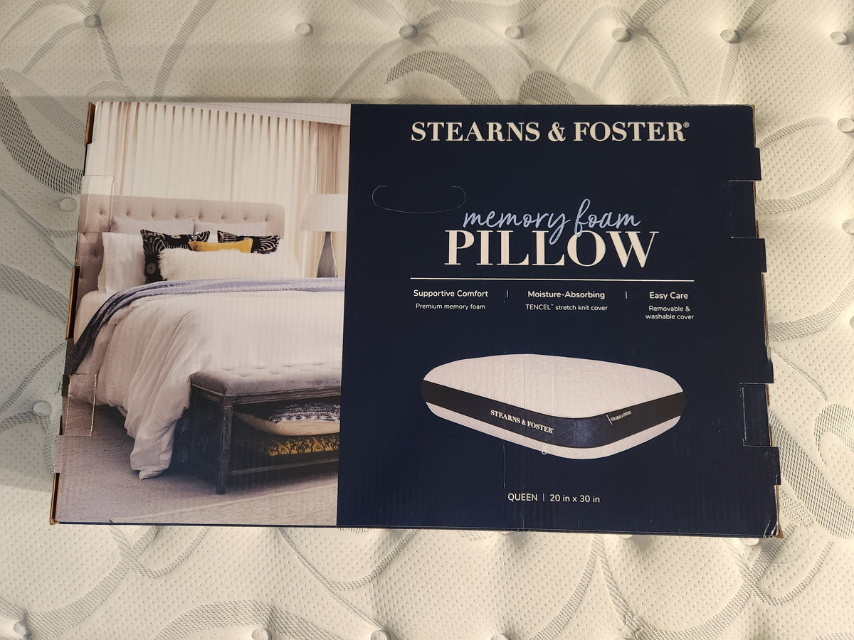 A box of the Stearns & Foster Memory Foam Pillow rests on the mattress, featuring an inviting bedroom image. This pillow's conforming memory foam design offers comfortable support to ensure restful nights.
