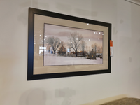 A picturesque landscape painting titled "Outside Of Bally" by Picture Depot adorns the white wall, illustrating bare trees and a small building against a snowy backdrop in a Glass Art Frame.