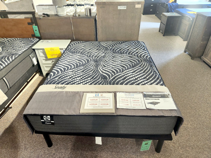 Sealy mattresses in-store, displaying price tags and info cards, featuring firm cushioning RMDH H1 foam, surrounded by furniture.