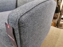 Close-up of a textured blue 37-59C Swivel Chair by Superstyle with a tag attached, offering comfortable support, placed on a grey carpet.