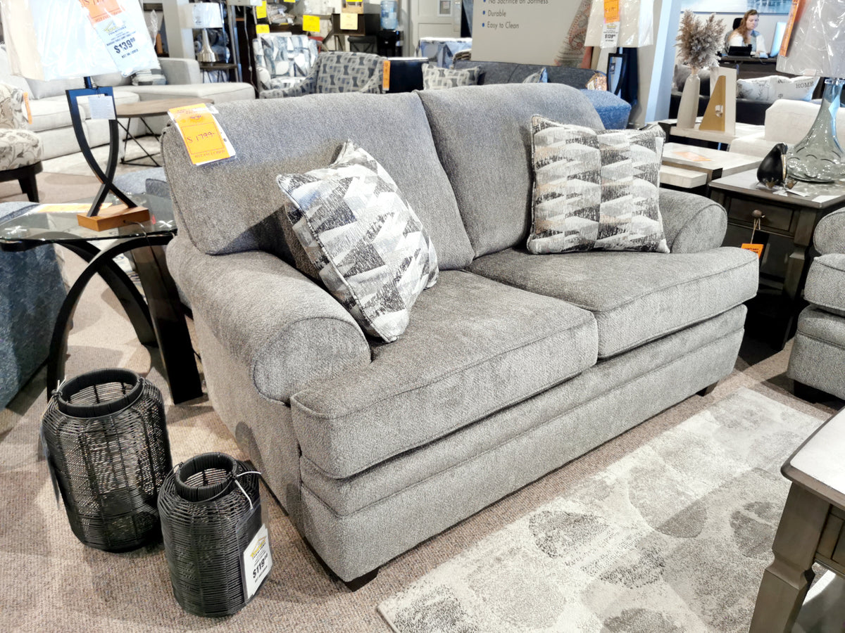 The 4610 Loveseat by Trendline, made in Canada, comes in gray with two patterned cushions and is displayed in a chic showroom.