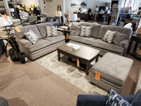 Trendline 4610 Loveseat with matching pillows, hardwood coffee table, and ottoman on a carpet in a furniture showroom.