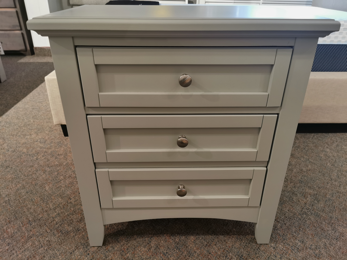 A compact, light gray two-drawer nightstand from Vaughan Bassett's Bonanza bb26 collection, featuring satin nickel hardware and round handles, stands on a carpeted floor.