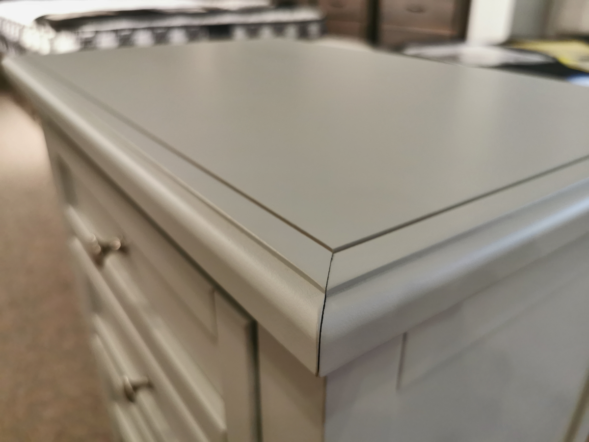 Close-up of the Vaughan Bassett Bonanza bb26 2-Drawer Nightstand, showcasing a smooth top surface and polished edge, adorned with satin nickel hardware. The two drawers are equipped with small handles.